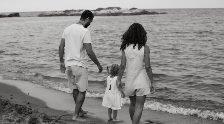 A family with a young daughter walks along a sandy beach shore during a summer vacation.