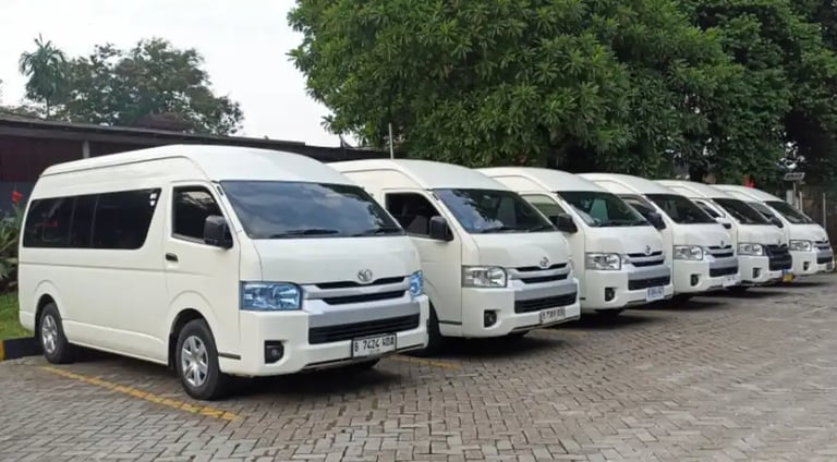Enam Toyota Hiace warna putih berjajar rapi di tempat parkir pandangan dari kanan depan.