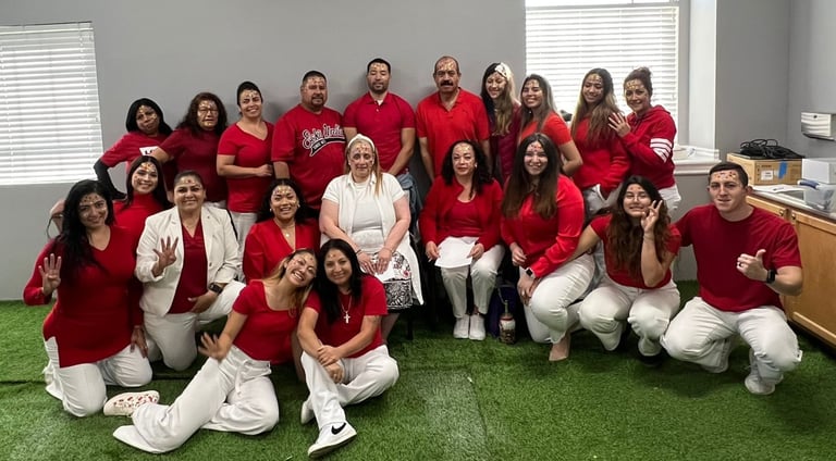 Diverse group of coworkers posing in red shirts and white pants for a workplace team building event.