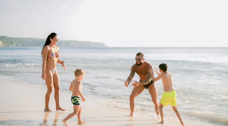 Children playing in the shoreline waves during a fun family beach photography session at Dreamland Beach Bali.
