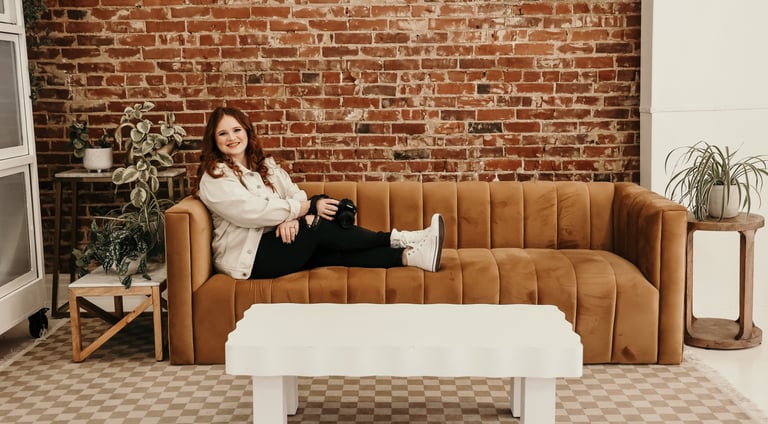 Rachel sits on a couch smiling at the camera