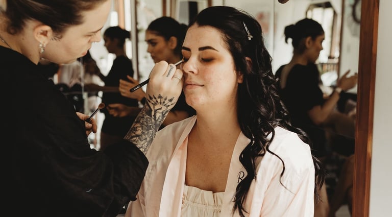 a woman getting her makeup done by a makeup artist