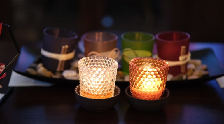 Two lit beeswax votive candles, side by side on a table