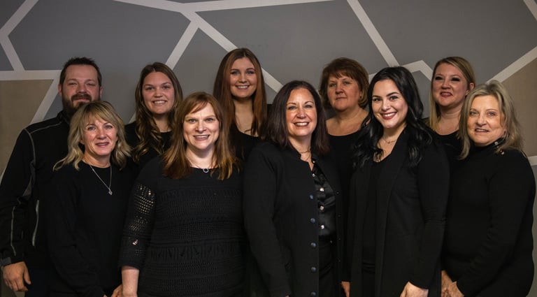 A diverse team of professional colleagues smiling together in front of a modern geometric wall mural.