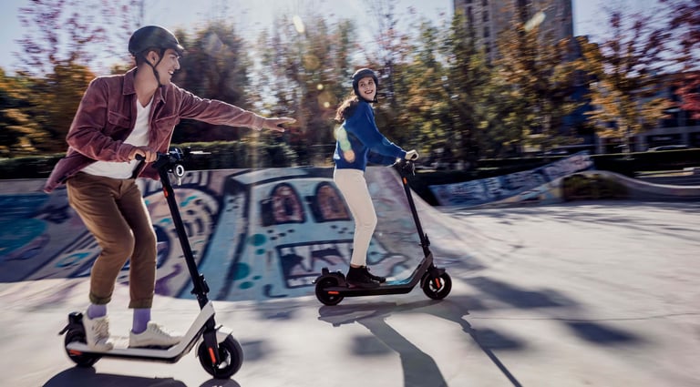 a man and woman riding scooters in a skateboard park