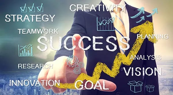 A person in a suit points to the word "SUCCESS" on a digital screen with words vision, innovation, research, strategy