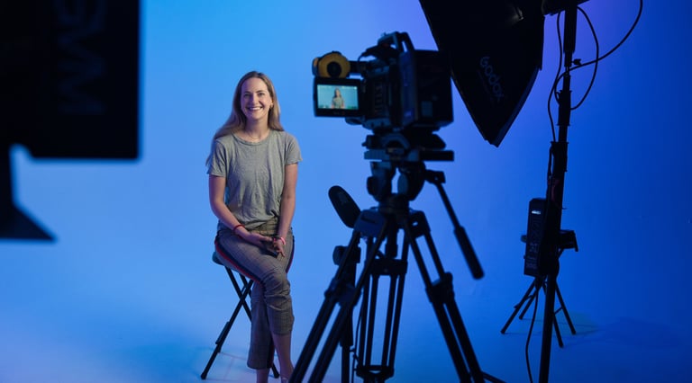 a woman sitting on a chair in front of a camera