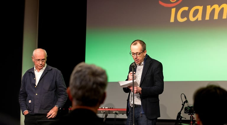 Un homme en veste noire un micro à la main