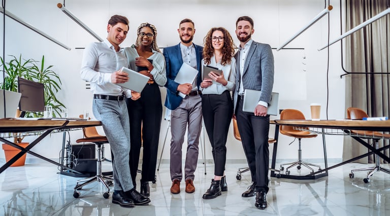 a group of people standing around a table with laptops