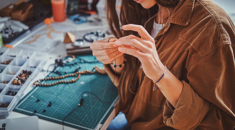 Una diseñadora de joyería creando collares y pulseras de cuentas hechos a mano en un taller creativo