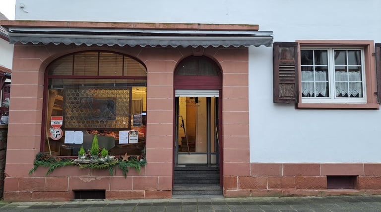 Fassade eines Metzgereigeschäfts mit Ladenschild, Schaufensterdekoration und Eingangstür