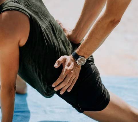 Lower back massage being done by applying pressure while client is in a stretch