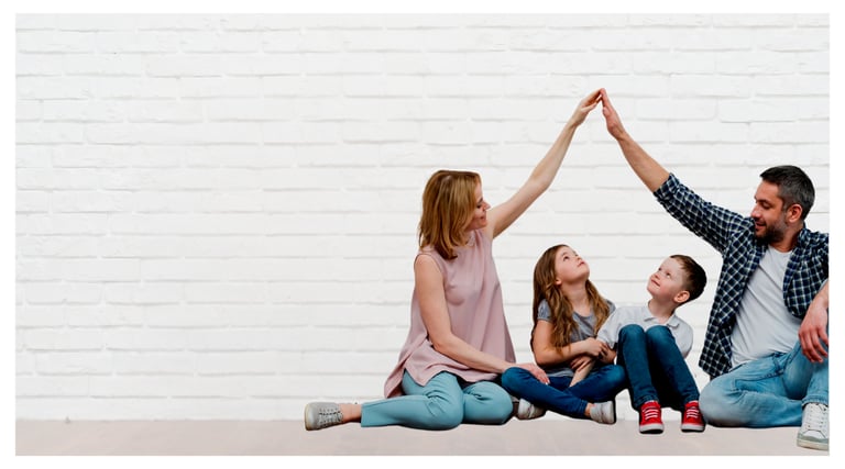 A happy family creates a roof shape with their hands in front of a white brick wall, symbolizing home security.