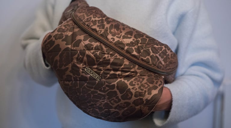 Une femme portant une banane léopard qui a les mains dans la poche kangourou de la banane