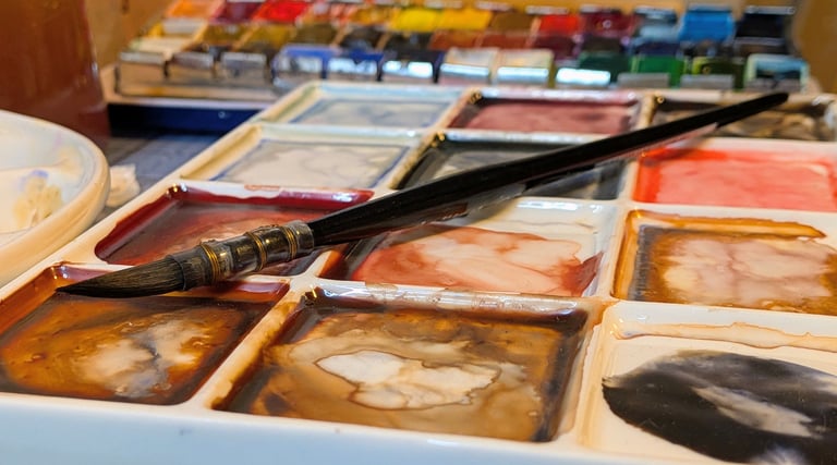 Waterverf palet met penseel en aquarel napjes, gemengde kleuren op een bord