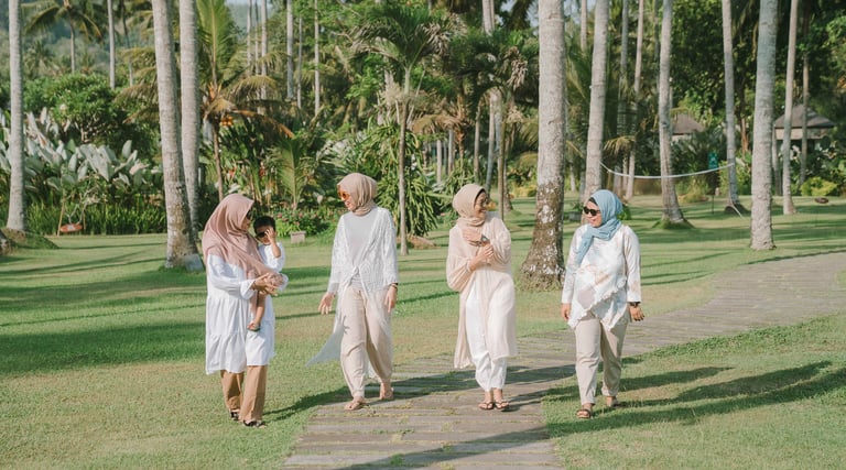 Friends walking together across palm garden lawn during photoshoot at Candi Beach Resort Karangasem Bali