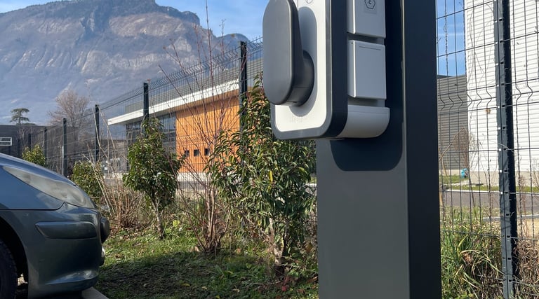 a parking meter with a car parked in front of a fence