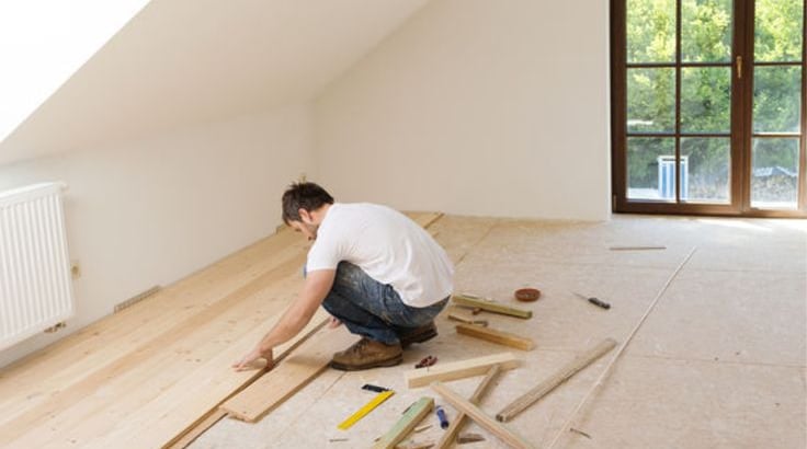 illustration d'un ouvrier posant du parquet en bois massif dans une pièce baignée de lumière 