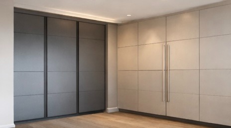 Modern custom built-in wardrobes with sleek grey sliding doors and beige paneled cabinetry.