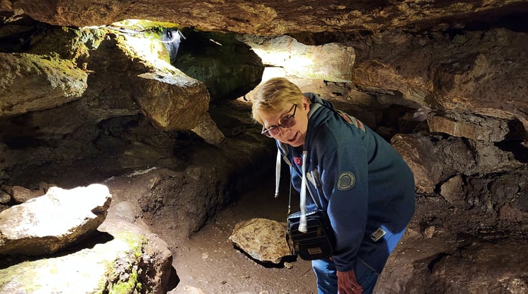 Low ceilings for Lady in Badgers Cave at Blarney Castle in Ireland
