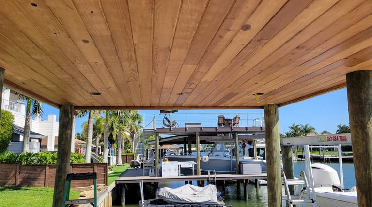 Custom tongue and groove ceiling installation on a boat dock overlooking a canal with luxury yachts.