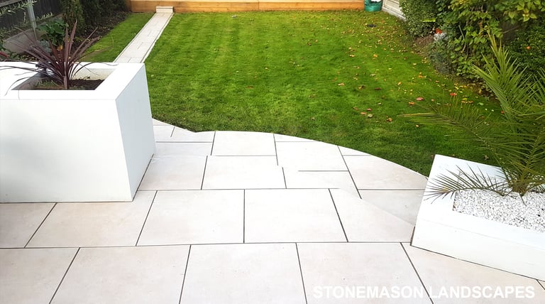 Modern chic raised porcelain patio with white rendered walls and planters