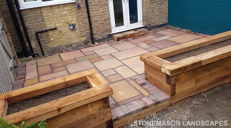 Colourful sandstone patio with raised wooden timber planter seating