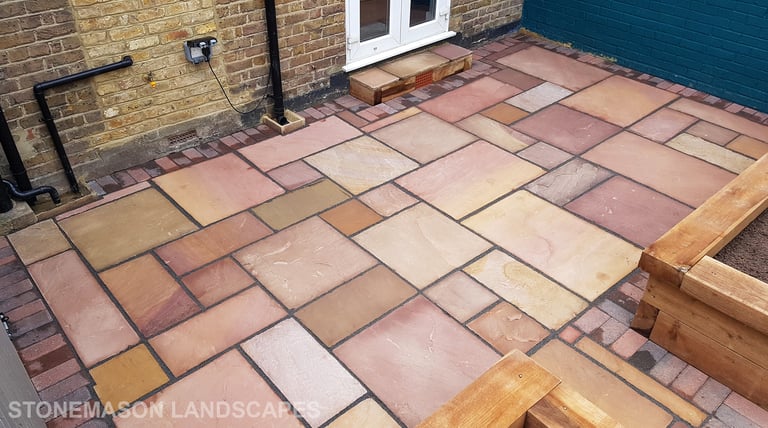 Colourful sandstone patio with raised wooden timber planter seating