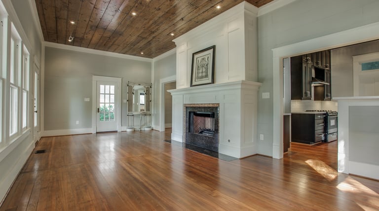 Modern living room with rustic wood ceiling, hardwood floors, and a white fireplace mantel.
