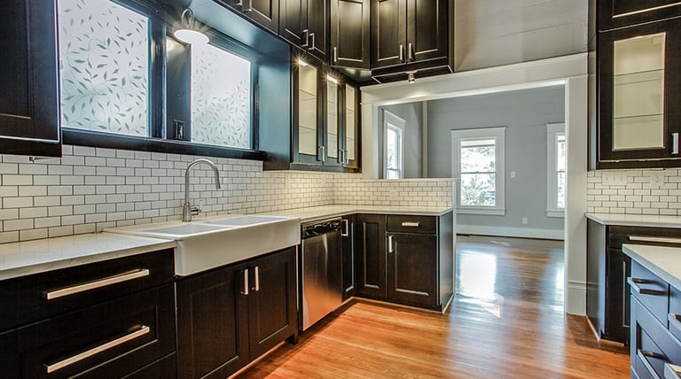 Modern kitchen with black shaker cabinets, white subway tile backsplash, and farmhouse sink.