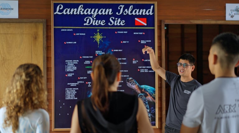 Dive guide giving a dive briefing to three divers at a site map at Lankayan Island
