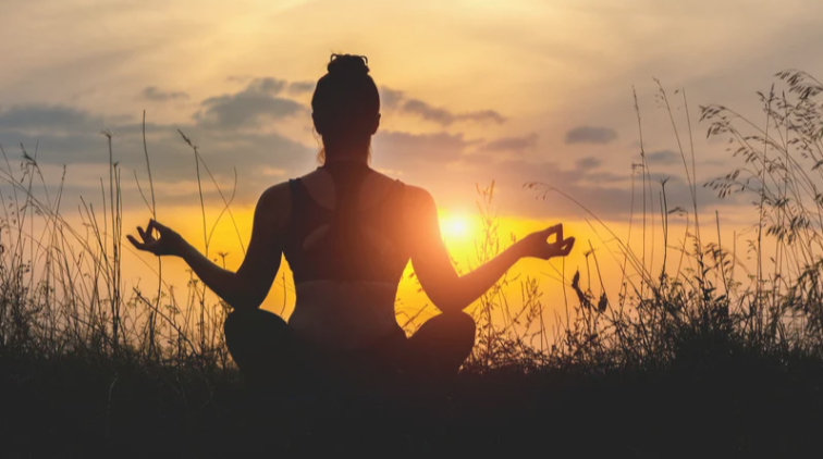 femme de dos en position de méditation en exterieur