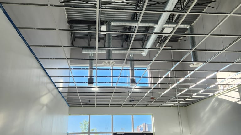 Commercial suspended ceiling grid installation with exposed T-bar system and lighting infrastructure