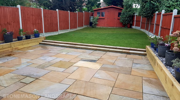 Large sandstone patio and raised wooden sleeper planters