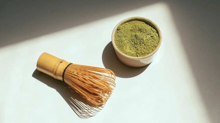 Close-up of vibrant green matcha powder and bamboo whisk