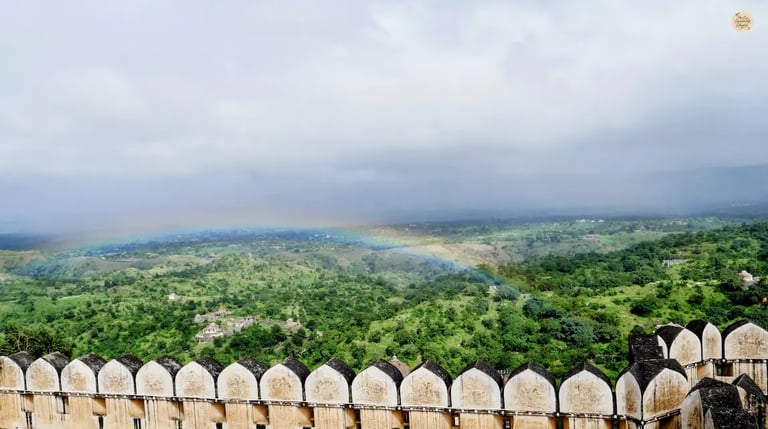 Rainbow visible from Badal Mahal at Kumbhalgarh Fort, overlooking the lush Aravalli hills and fort surroundings.
