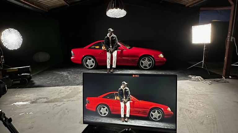 homme dans un studio video sur fond noir avec une voiture mercedes rouge éclairée par des lumières