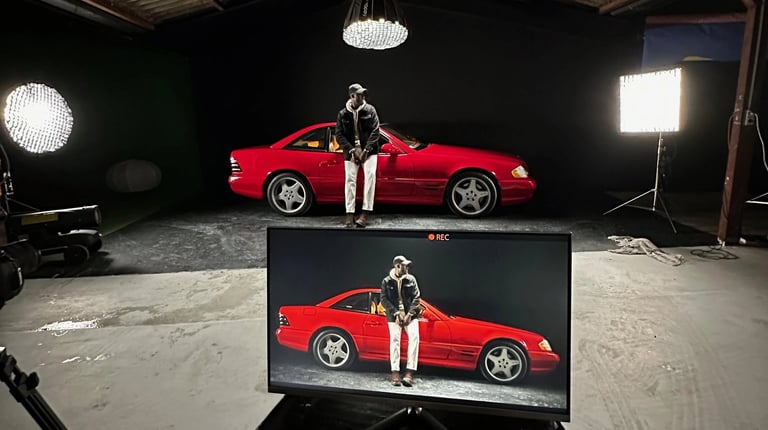 homme dans un studio video sur fond noir avec une voiture mercedes rouge éclairée par des lumières