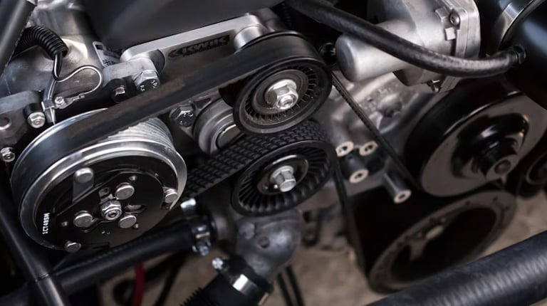 A mechanic holds up and compares a dirty, used car cabin air filter with a new, clean white filter in an automotive workshop