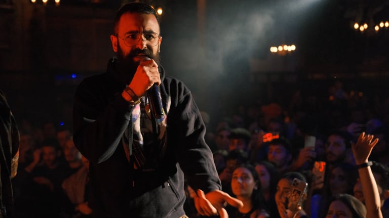 a man in a black jacket and a microphone in front of a crowd, rapper, beatlalipos, concert, rap, 