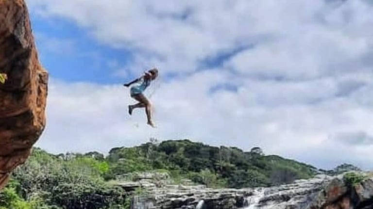 Lady jumping out of Baboon cave with Strandlooper falls behind her