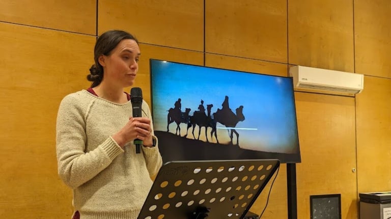 One of our church family preaching from the bible in front of a screen.