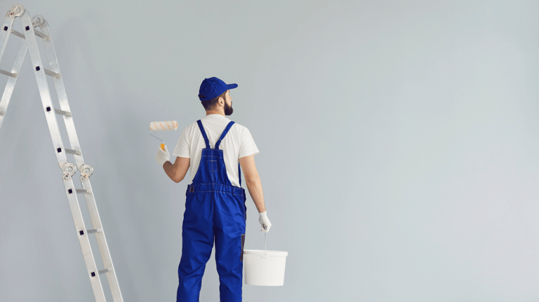 a man in blue overalls and a bucket hat, holding a paint roller