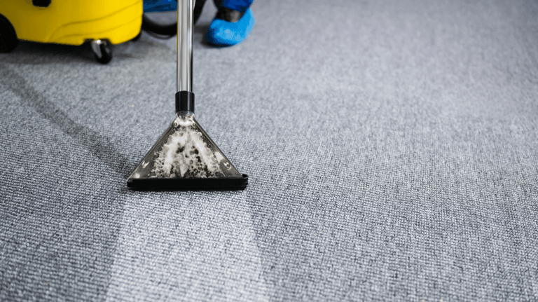 a person cleaning a carpet with a broom