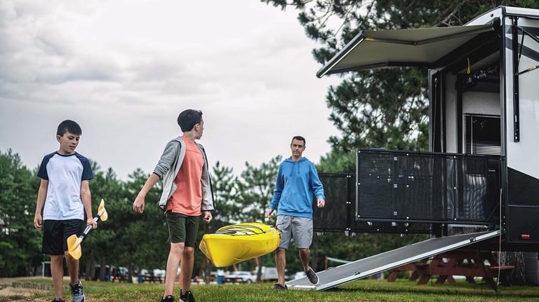 a group of people walking around a trailer carrying a canoe
