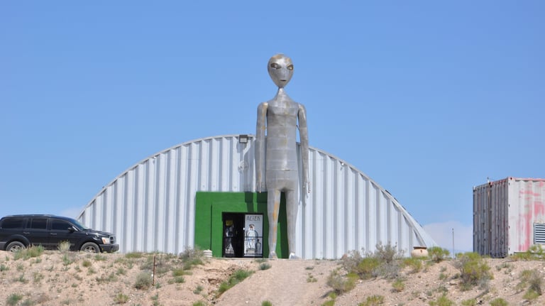 a statue of a alien standing in front of a building