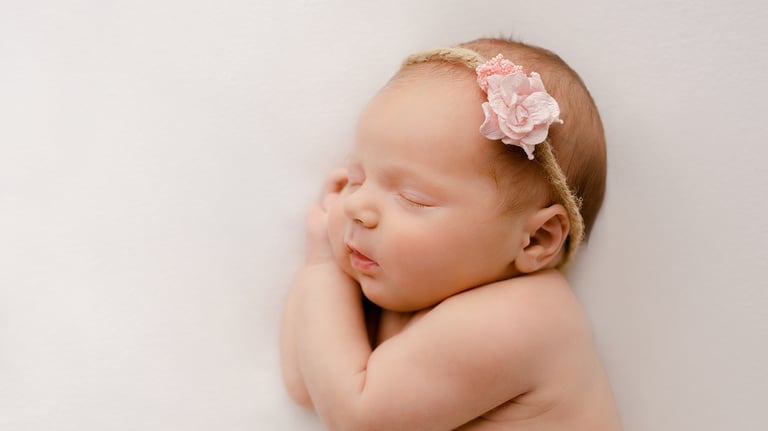 a baby girl sleeping on her side with her hands on her chin