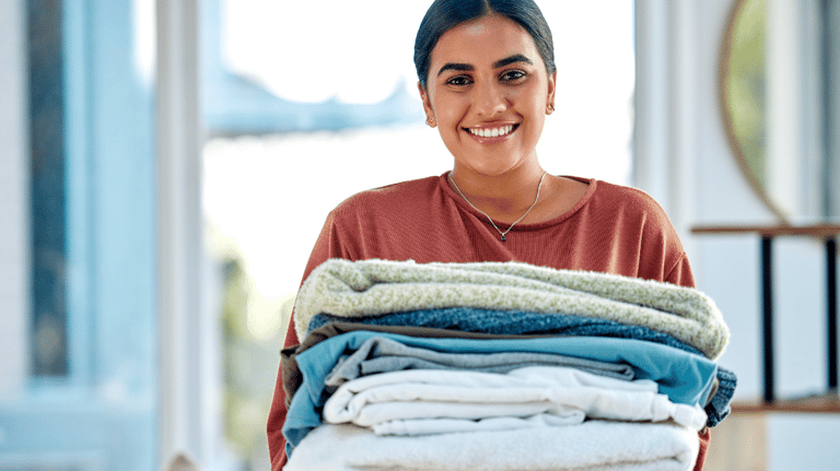 a woman holding a stack of folded towels
