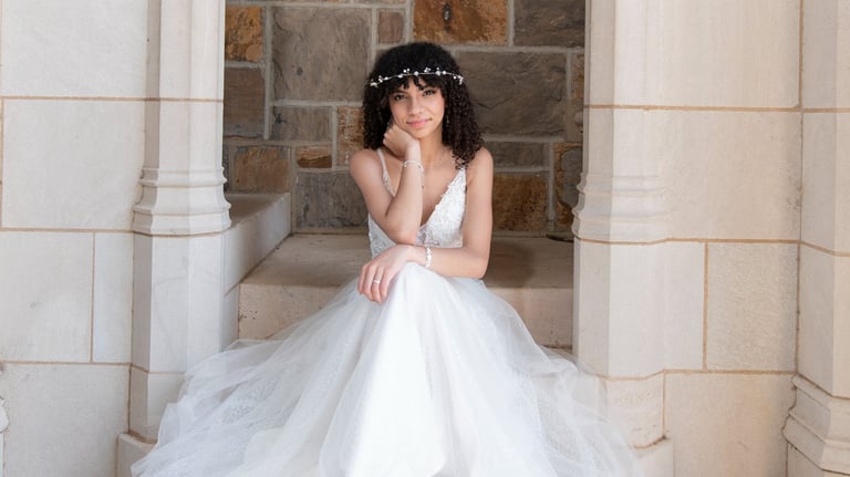 quinceanera in a white dress sitting on a stone stepstone