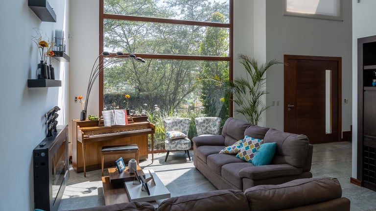 fotografía inmobiliaria quito ecuador tumbaco  gran sala de estar con muebles, piano y un gran ventanal con luz natural